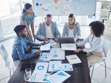 Business professionals discussing documents around a table in a modern office