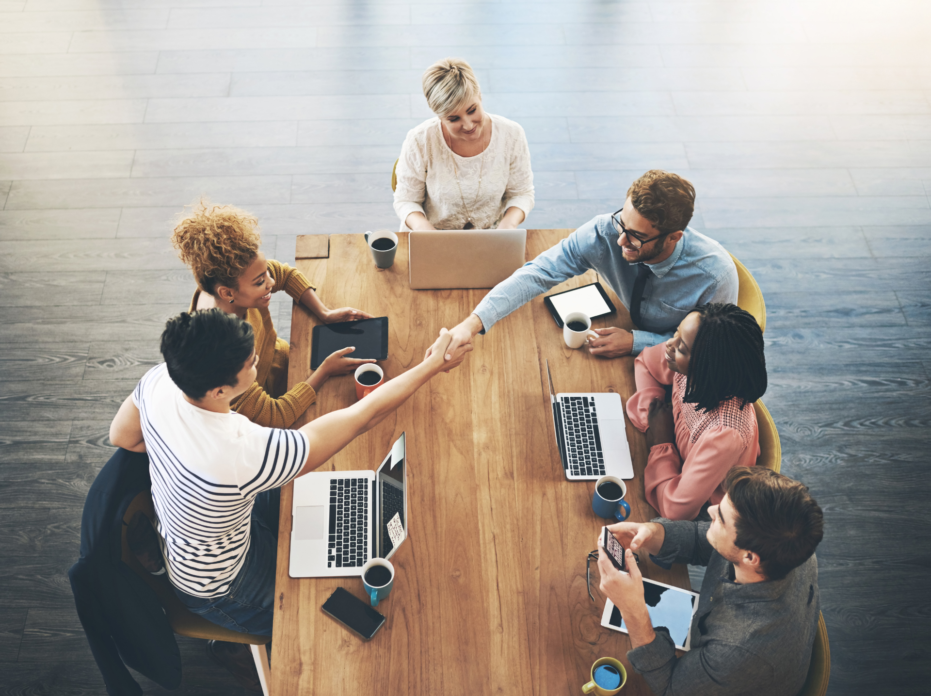  A diverse group of individuals collaborating around a table, each engaged with their laptops in a productive setting.