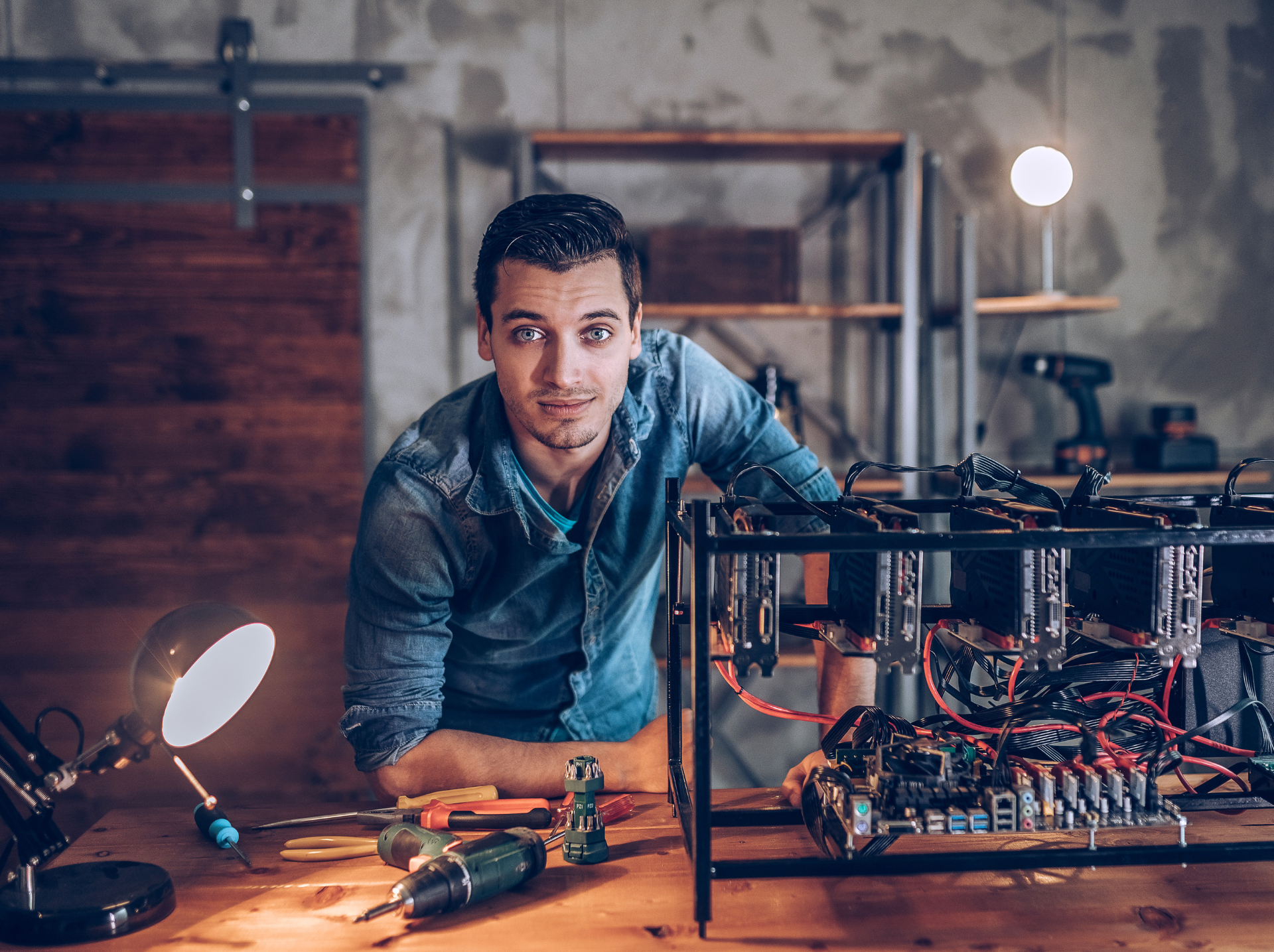 A man working on a tech project, surrounded by tools and equipment, possibly assembling a computer or electronics setup
