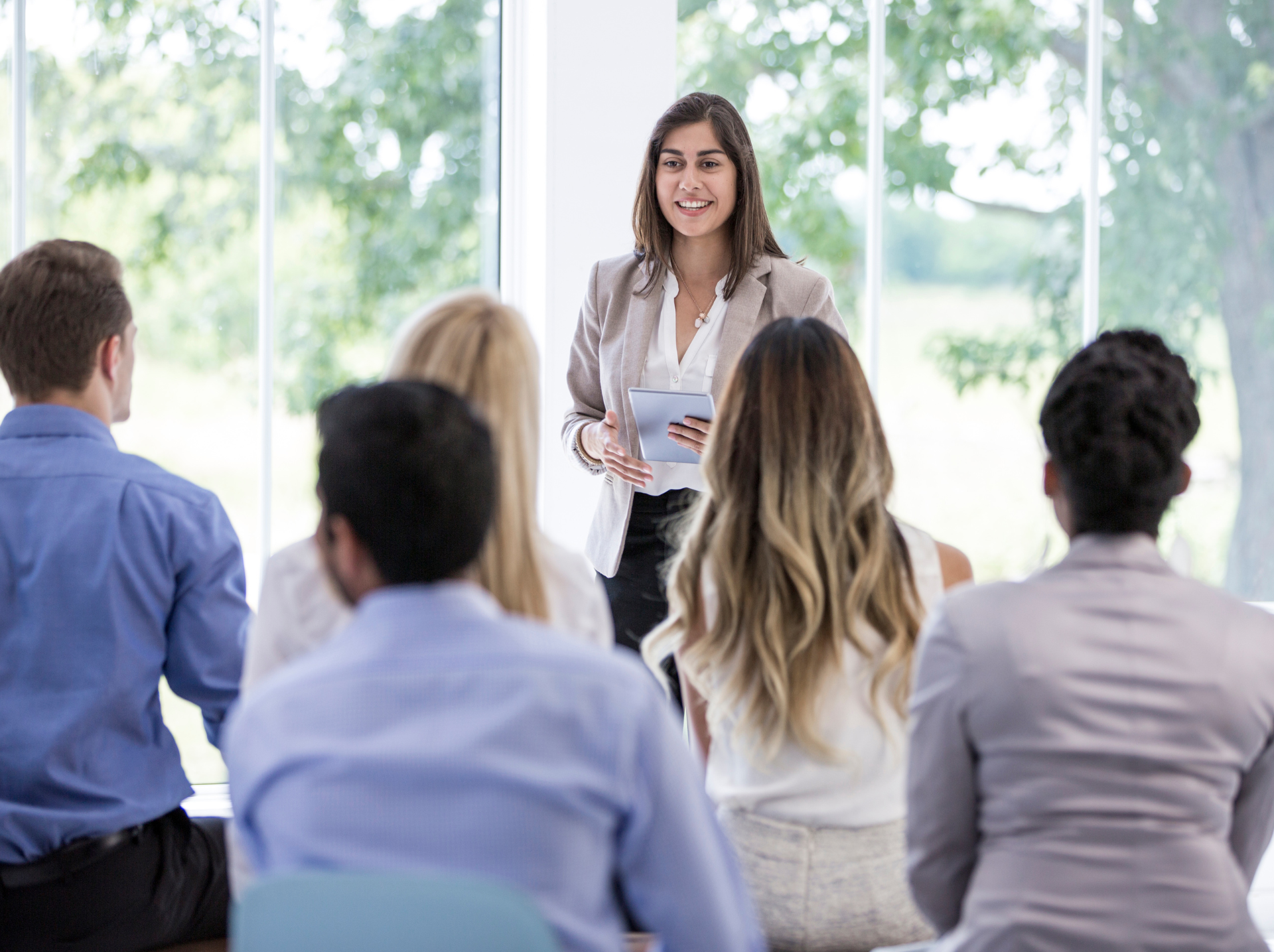 A woman presents to an audience, engaging them with her speech and visual aids in a professional setting