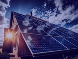 A residential house equipped with solar panels on the roof, with the sun shining in the background, symbolizing the harnessing of solar energy for sustainable living
