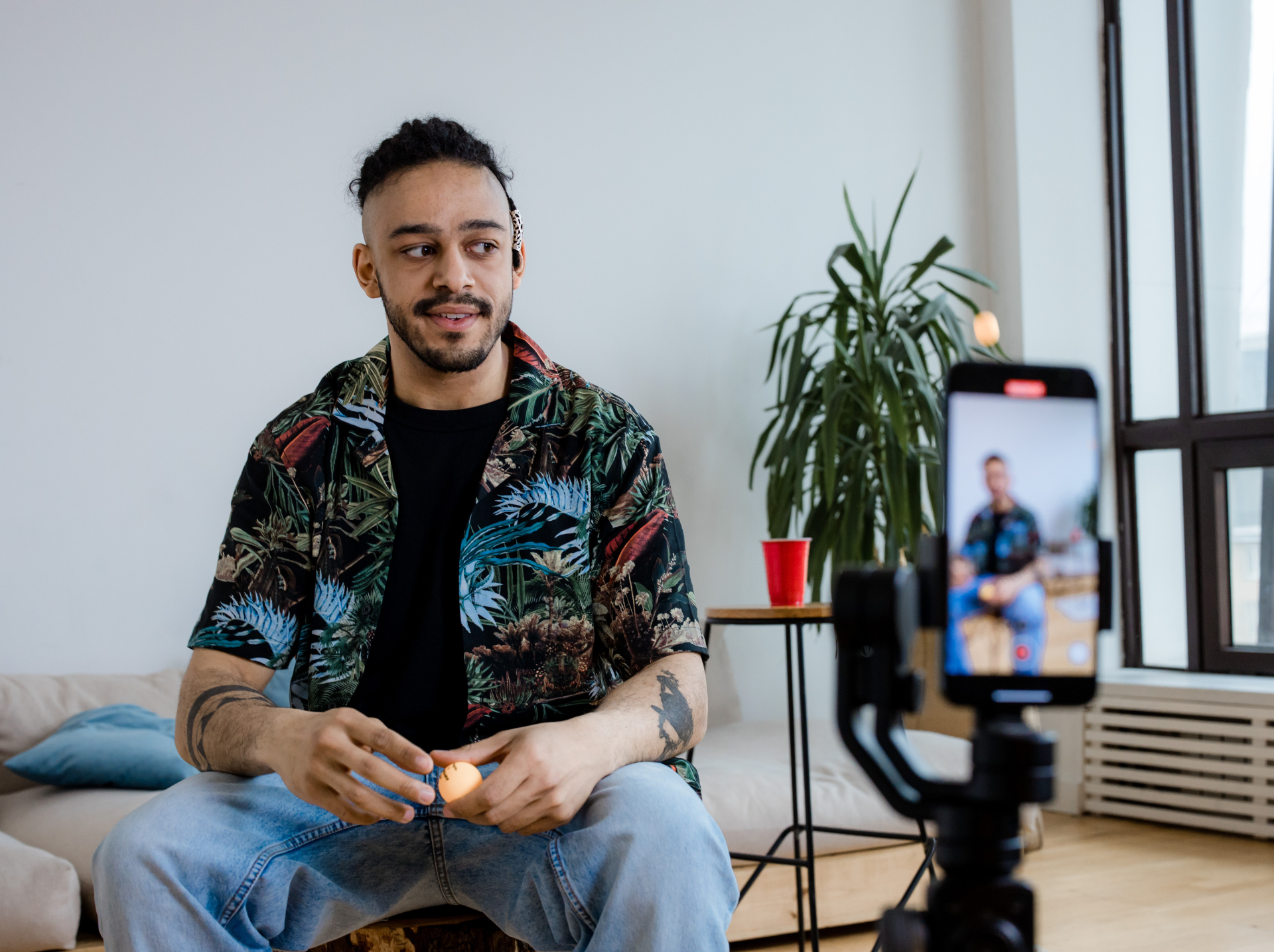 A man seated on a couch, focused on a camera positioned in front of him, ready to capture ephemeral content.