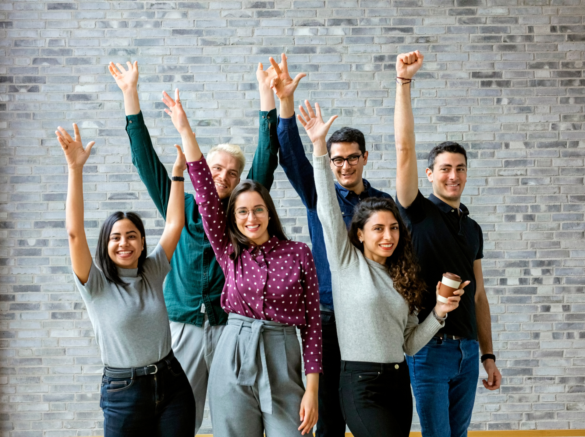 A diverse group of young individuals joyfully raising their hands in the air, expressing enthusiasm and unity.